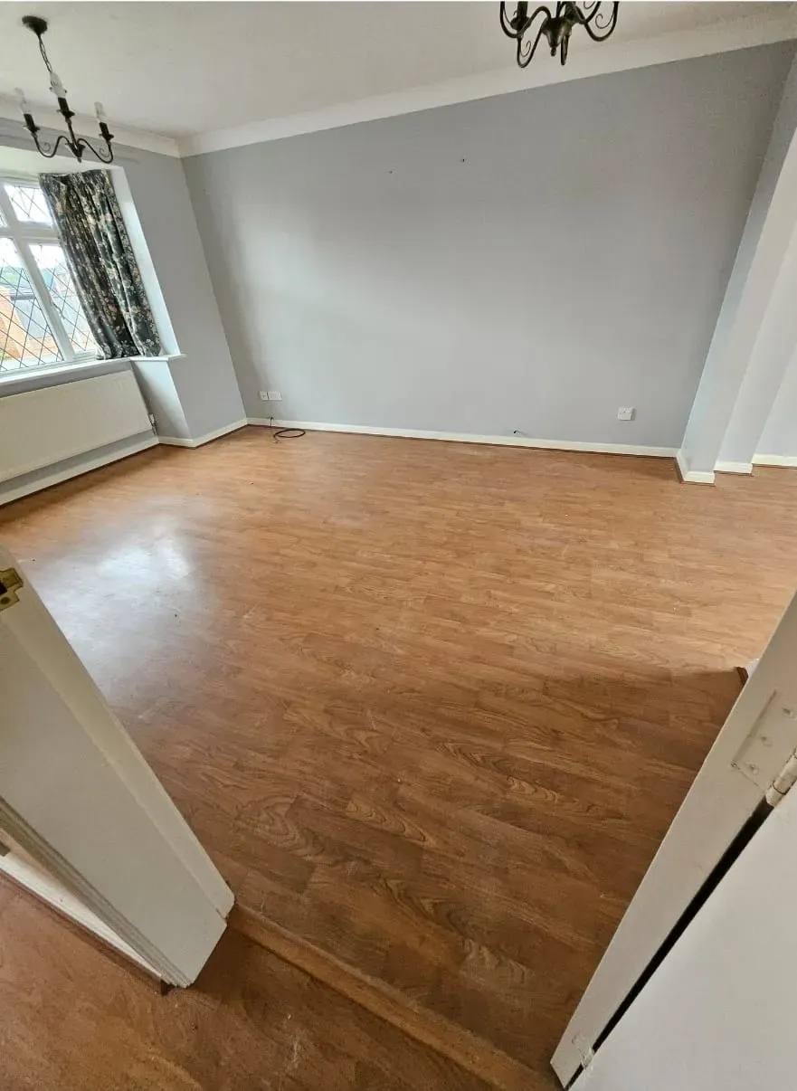 A freshly cleared and clean empty room with wooden laminate flooring and light grey walls, ready for new tenants or occupants after a house clearance service.
